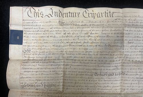 fig 1. An 1782 handwritten George III vellum tripartite legal indenture featuring ornate calligraphy, a blue revenue stamp, and three red wax seals along the bottom edge.