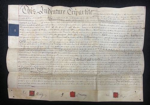 fig 2. An 1782 handwritten George III vellum tripartite legal indenture featuring ornate calligraphy, a blue revenue stamp, and three red wax seals along the bottom edge.