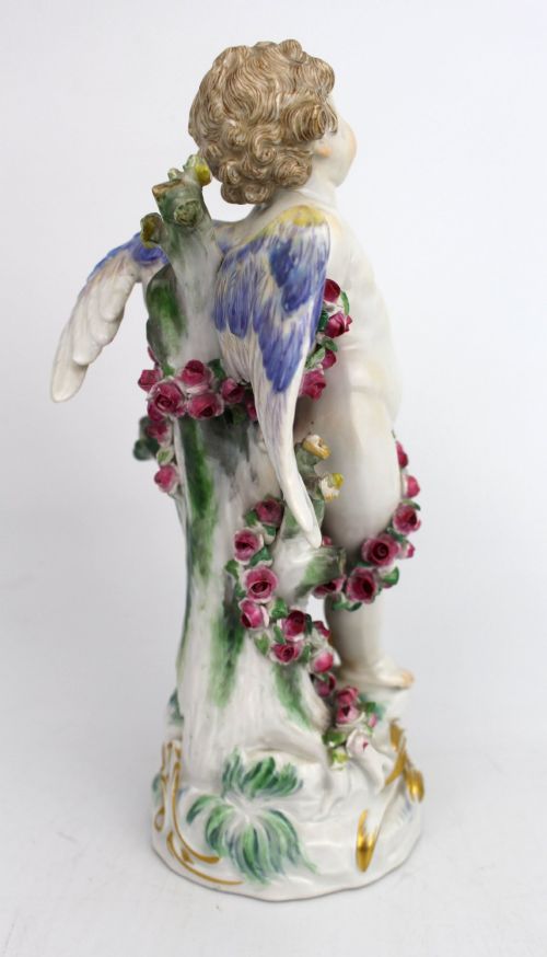 fig 2. A Meissen hard-paste porcelain figurine depicting a winged cupid bound with a pink rose garland, standing on a gilded scrollwork base.