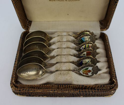 fig 1. A cased set of six sterling silver demitasse spoons featuring colourful enamelled crest finials set inside a textured brown presentation box.