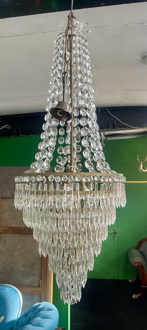 fig 1. A French Empire style crystal waterfall chandelier with upper octagonal bead strands and lower cascading glass prisms attached to a brass band.
