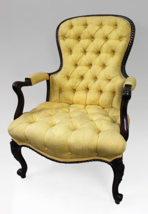 fig 1. A Victorian mahogany button-back armchair with yellow tufted fabric upholstery, padded armrests, and carved cabriole front legs.