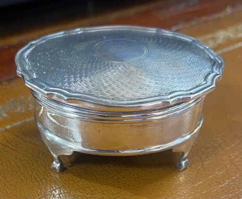 fig 1. An oval sterling silver trinket box featuring an engine-turned wave pattern on the lid and resting on four small feet.