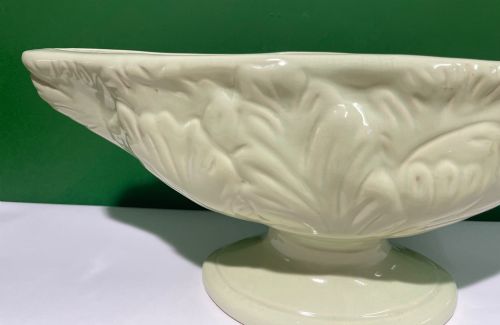 fig 1. A pale cream glazed ceramic boat-shaped vase featuring embossed lotus leaf reliefs raised on a circular pedestal foot.