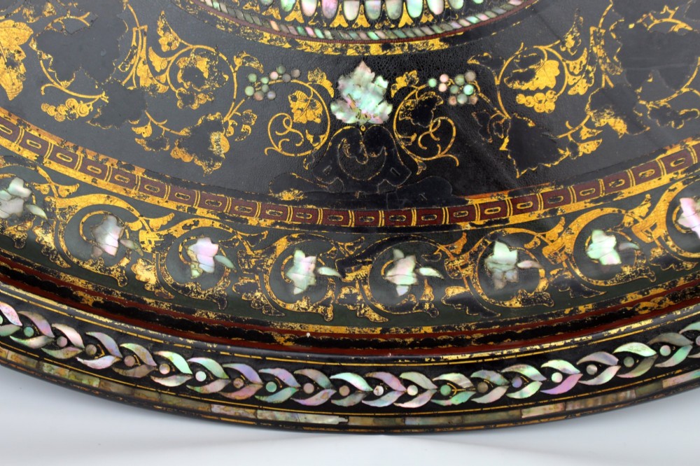 An oval Victorian black lacquered papier-mache tray featuring ornate gilt floral scrolls and iridescent mother-of-pearl leaf inlays around a central medallion. View II