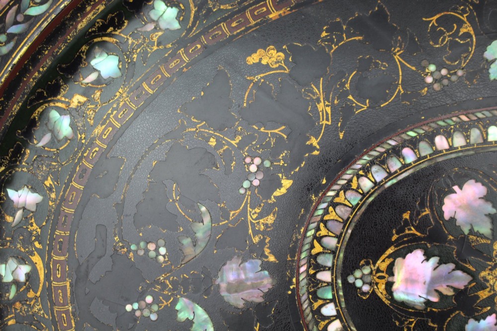 An oval Victorian black lacquered papier-mache tray featuring ornate gilt floral scrolls and iridescent mother-of-pearl leaf inlays around a central medallion. View IV