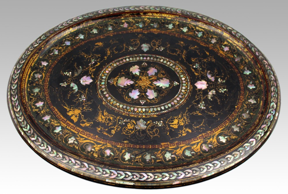 An oval Victorian black lacquered papier-mache tray featuring ornate gilt floral scrolls and iridescent mother-of-pearl leaf inlays around a central medallion. View VI