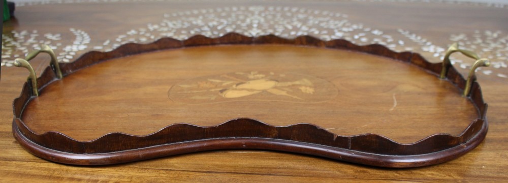 A kidney-shaped mahogany serving tray with central marquetry inlay, a scalloped gallery rim, and two brass handles.