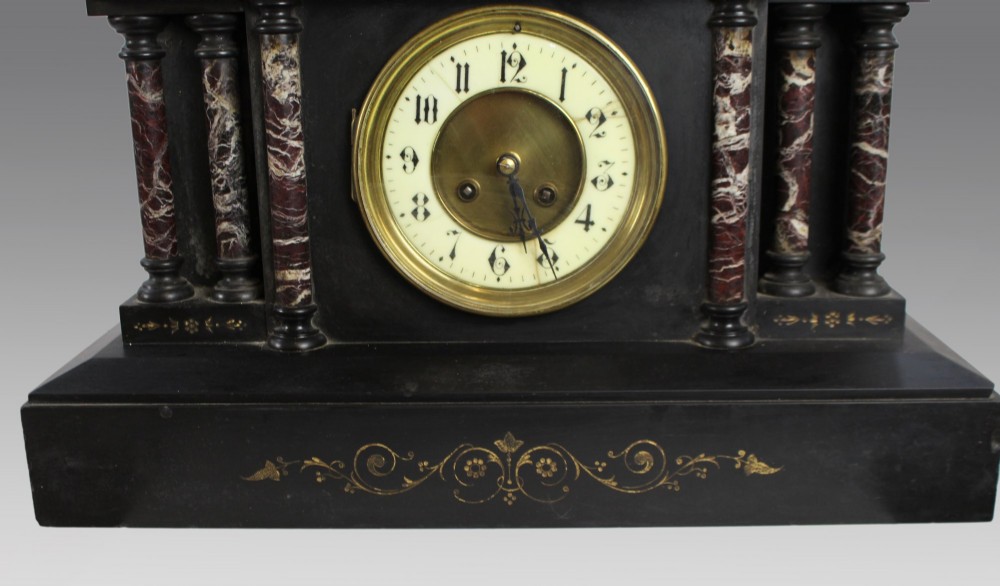 A High Victorian architectural mantel clock crafted from black slate with red rouge marble columns, a brass dial, and gilt floral engravings. View II