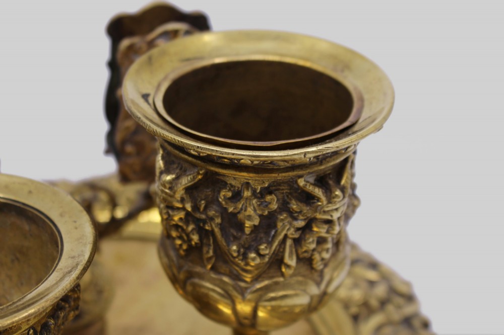 A 19th-century cast brass writing desk set featuring an ornate rimmed tray, two urn-shaped pots, and a small chamberstick. View X