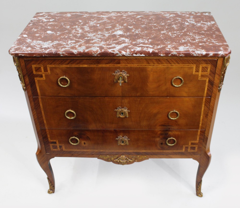 A French Louis XVI style mahogany and tulipwood three-drawer commode featuring geometric inlay, ormolu mounts, and a red mottled marble top. View II