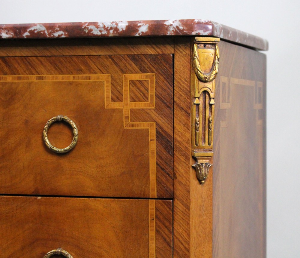 A French Louis XVI style mahogany and tulipwood three-drawer commode featuring geometric inlay, ormolu mounts, and a red mottled marble top. View VII
