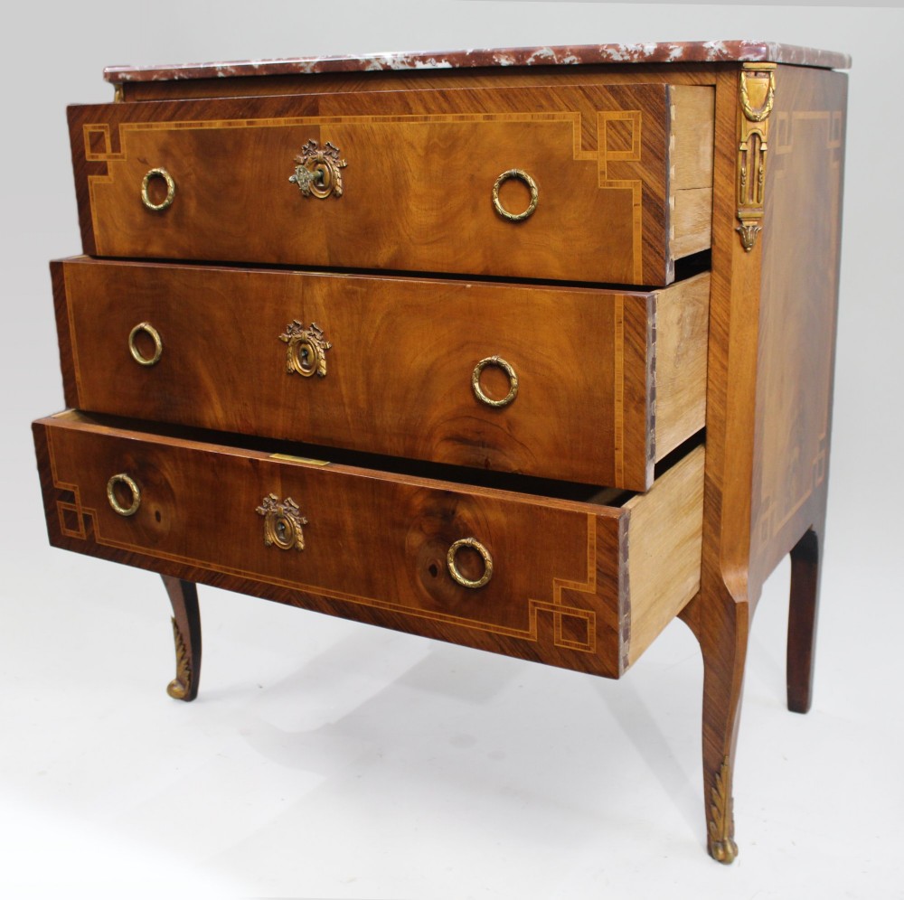 A French Louis XVI style mahogany and tulipwood three-drawer commode featuring geometric inlay, ormolu mounts, and a red mottled marble top. View XI