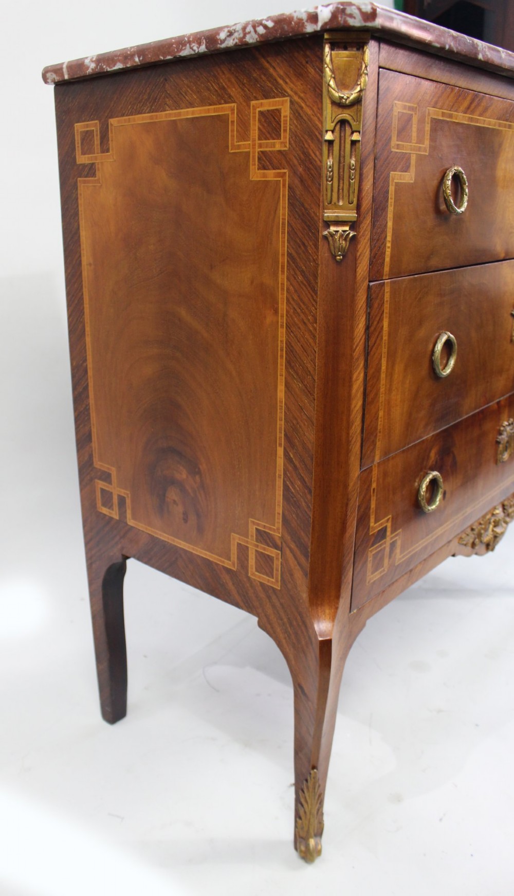 A French Louis XVI style mahogany and tulipwood three-drawer commode featuring geometric inlay, ormolu mounts, and a red mottled marble top. View XII