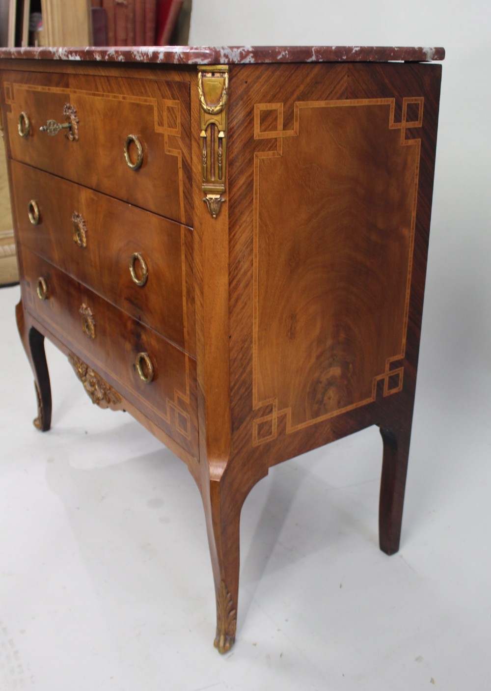 A French Louis XVI style mahogany and tulipwood three-drawer commode featuring geometric inlay, ormolu mounts, and a red mottled marble top. View XIII