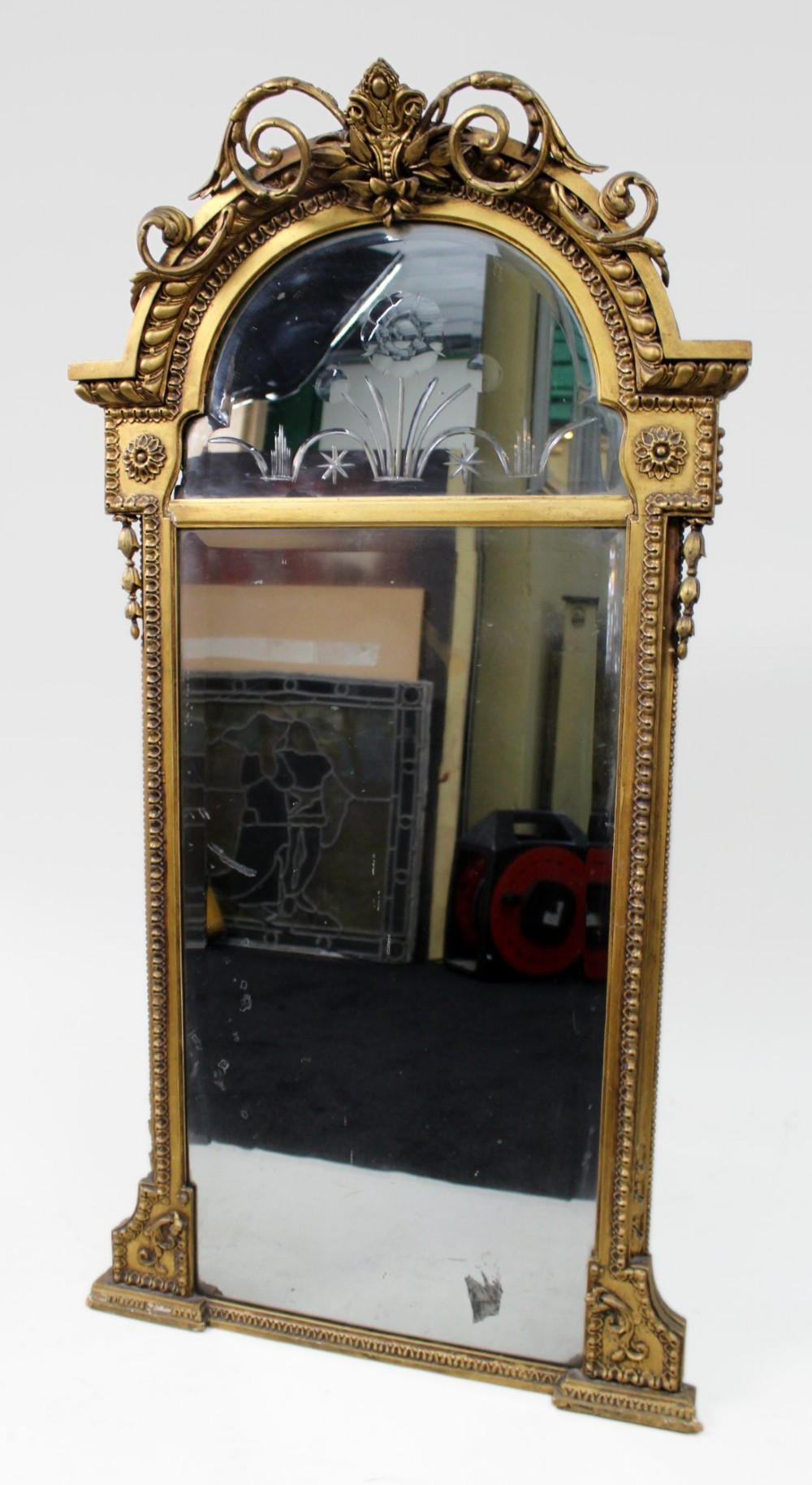 A Regency giltwood pier mirror with ornate cresting, beaded frame details, and an upper arched mirror section featuring intaglio cut floral designs.