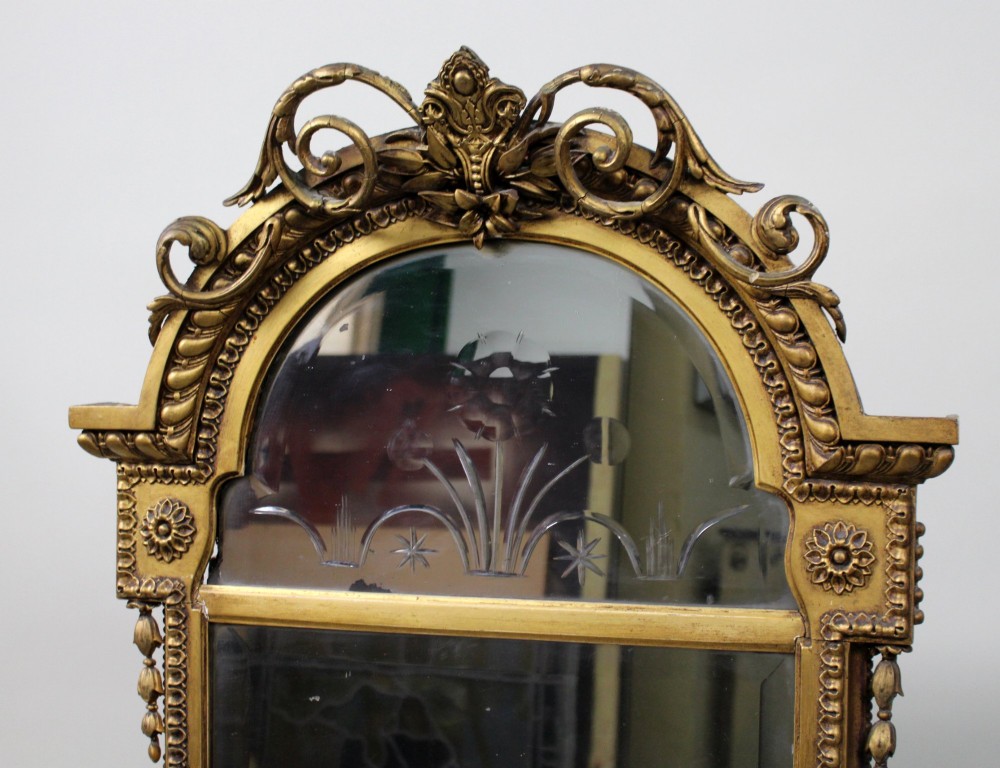 A Regency giltwood pier mirror with ornate cresting, beaded frame details, and an upper arched mirror section featuring intaglio cut floral designs. View IV