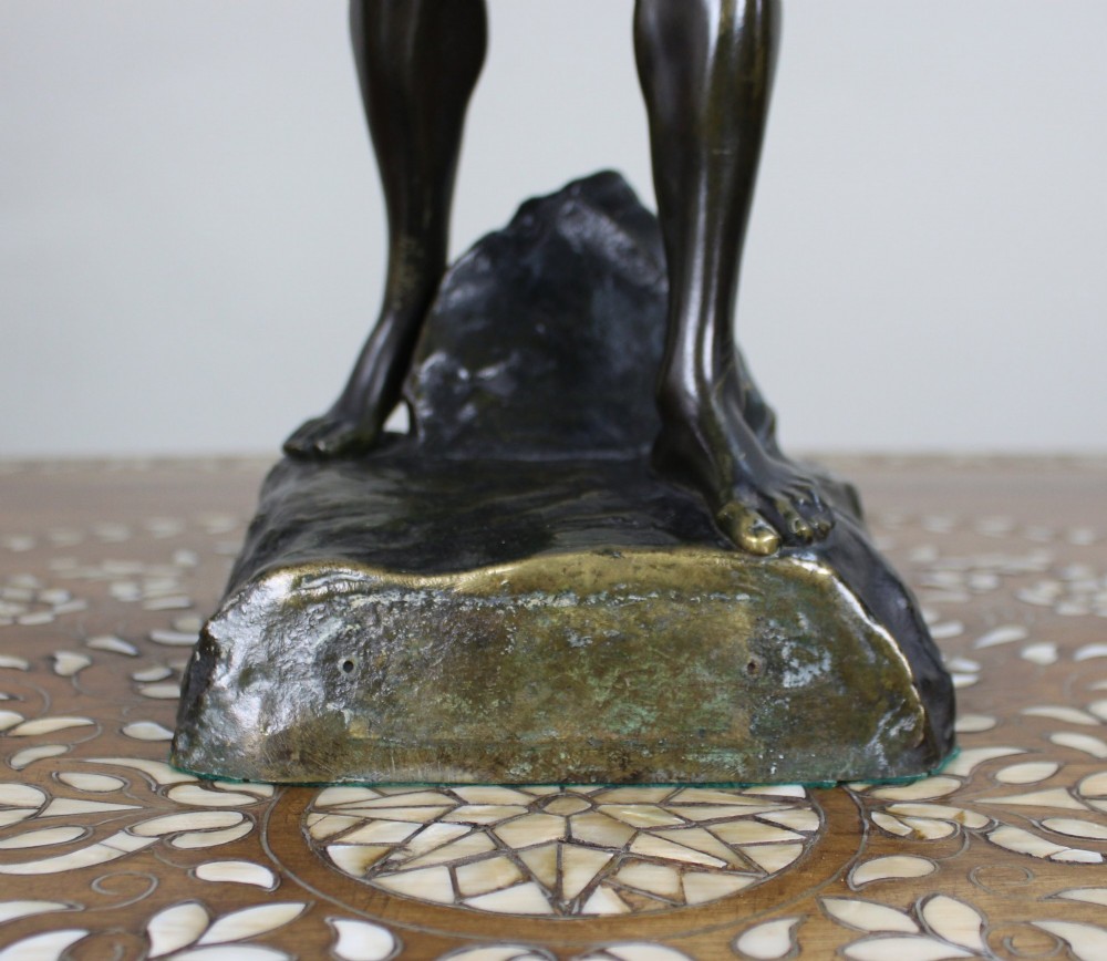 A dark brown patinated bronze figure of a classical male standing on a rocky base, holding a chalice in one hand and raising a laurel wreath aloft in the other. View VI