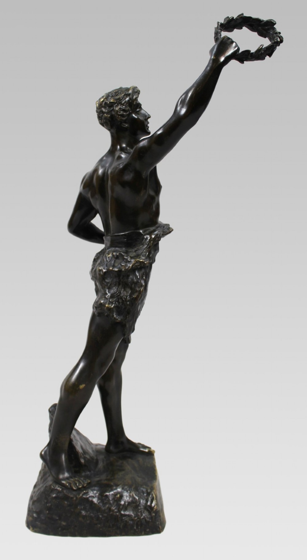 A dark brown patinated bronze figure of a classical male standing on a rocky base, holding a chalice in one hand and raising a laurel wreath aloft in the other. View XI