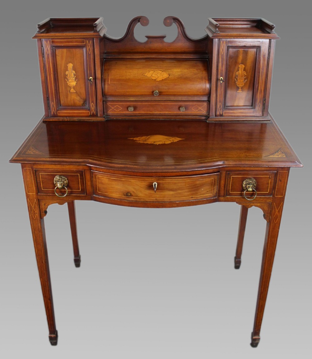 An Edwardian inlaid mahogany writing desk with a central drawer, satinwood urn marquetry, twin side cabinets, and tapered legs.