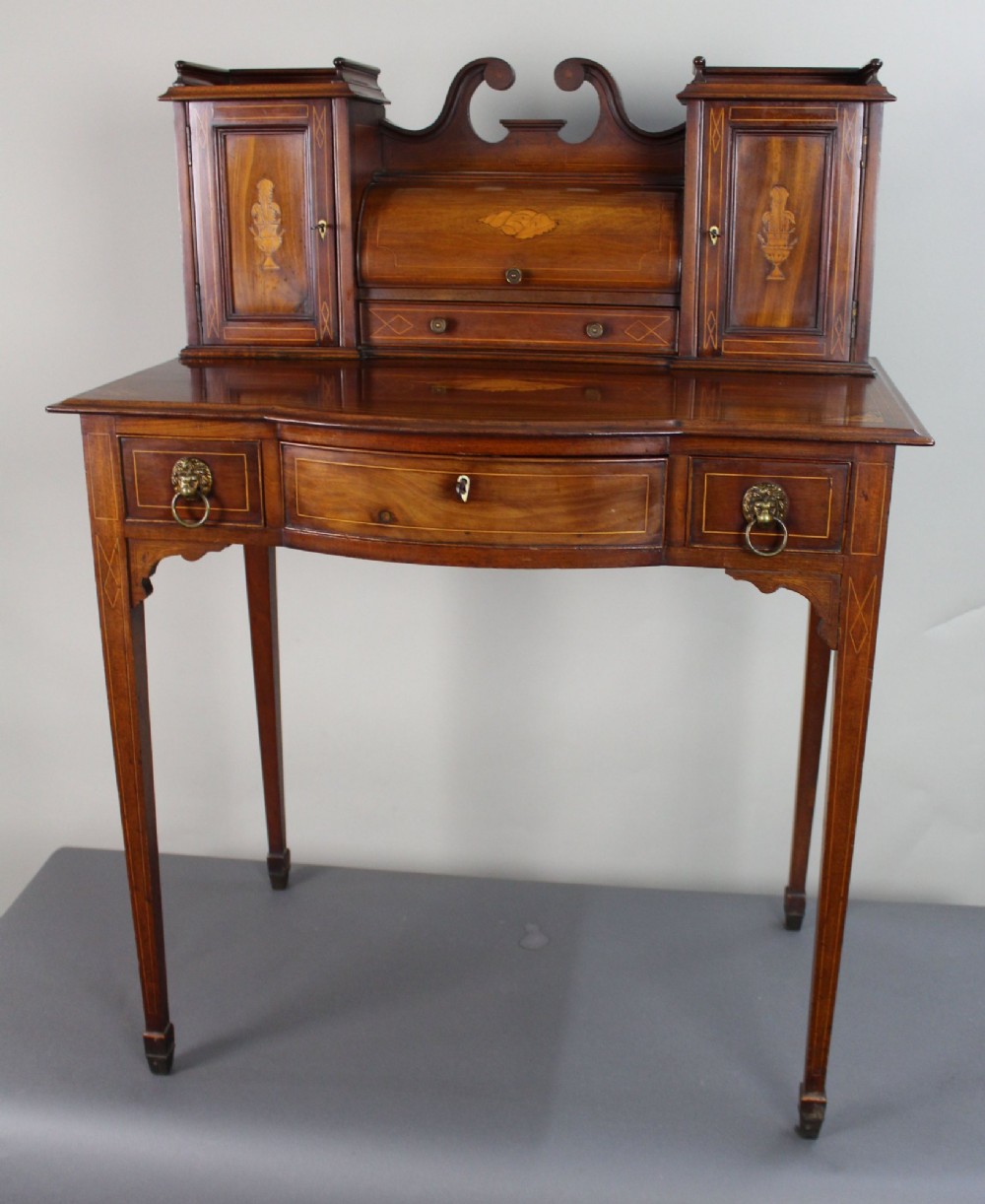 An Edwardian inlaid mahogany writing desk with a central drawer, satinwood urn marquetry, twin side cabinets, and tapered legs. View II