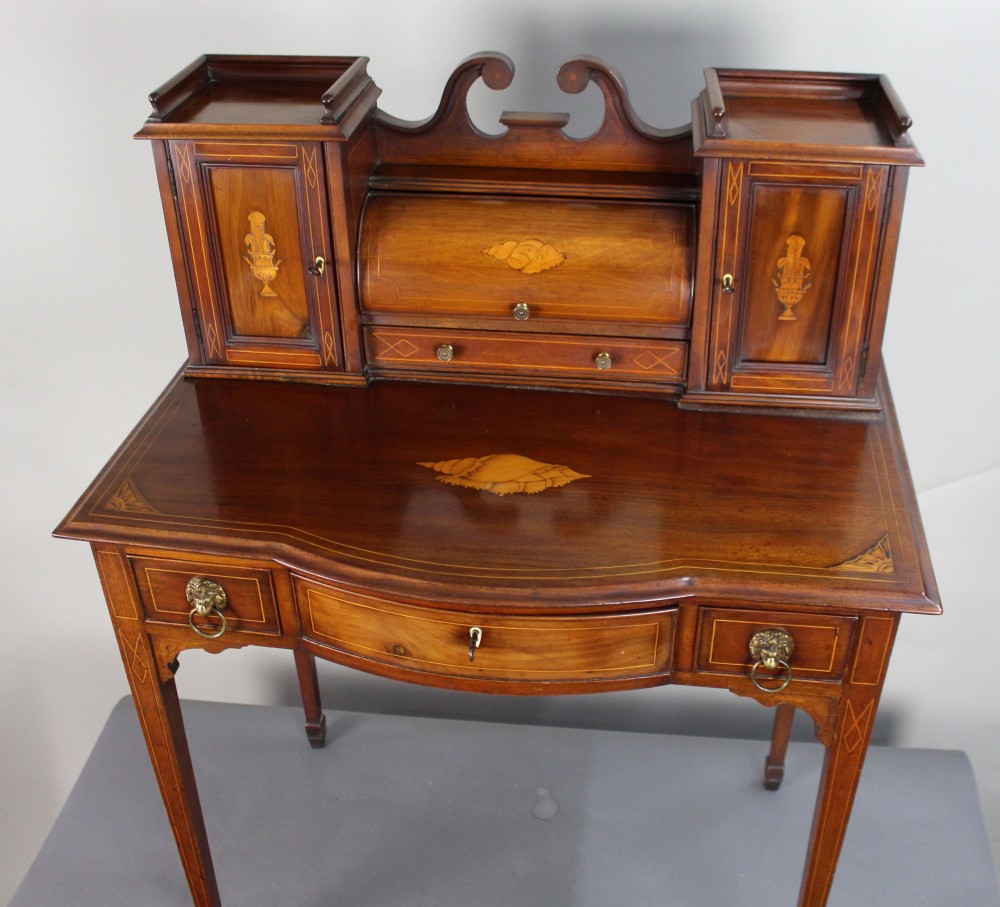 An Edwardian inlaid mahogany writing desk with a central drawer, satinwood urn marquetry, twin side cabinets, and tapered legs. View IV