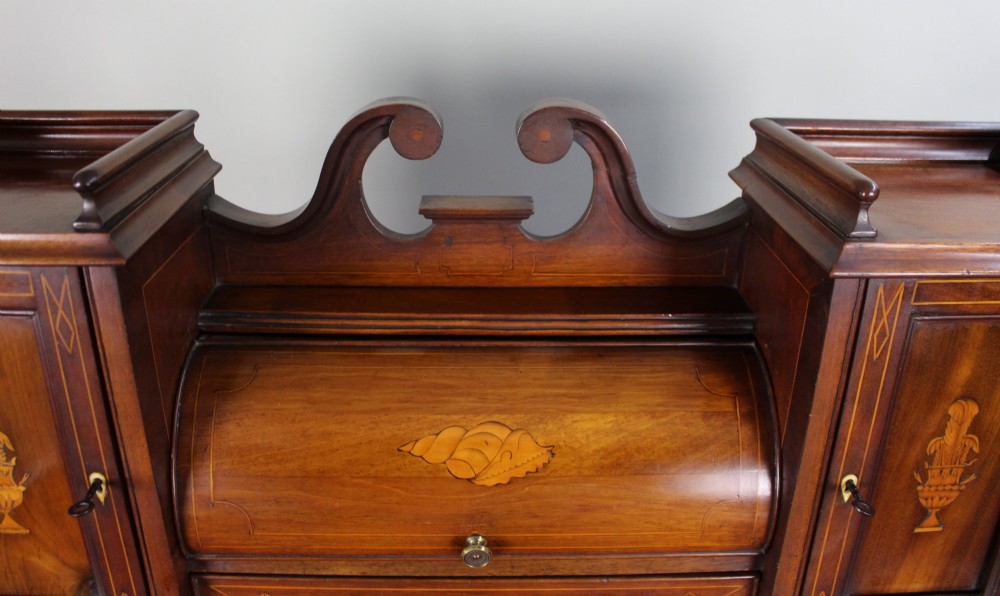 An Edwardian inlaid mahogany writing desk with a central drawer, satinwood urn marquetry, twin side cabinets, and tapered legs. View V