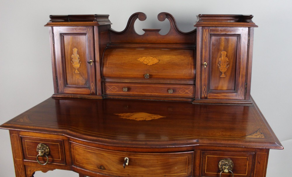 An Edwardian inlaid mahogany writing desk with a central drawer, satinwood urn marquetry, twin side cabinets, and tapered legs. View VI