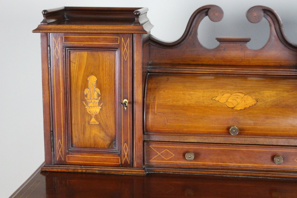 An Edwardian inlaid mahogany writing desk with a central drawer, satinwood urn marquetry, twin side cabinets, and tapered legs. View VII