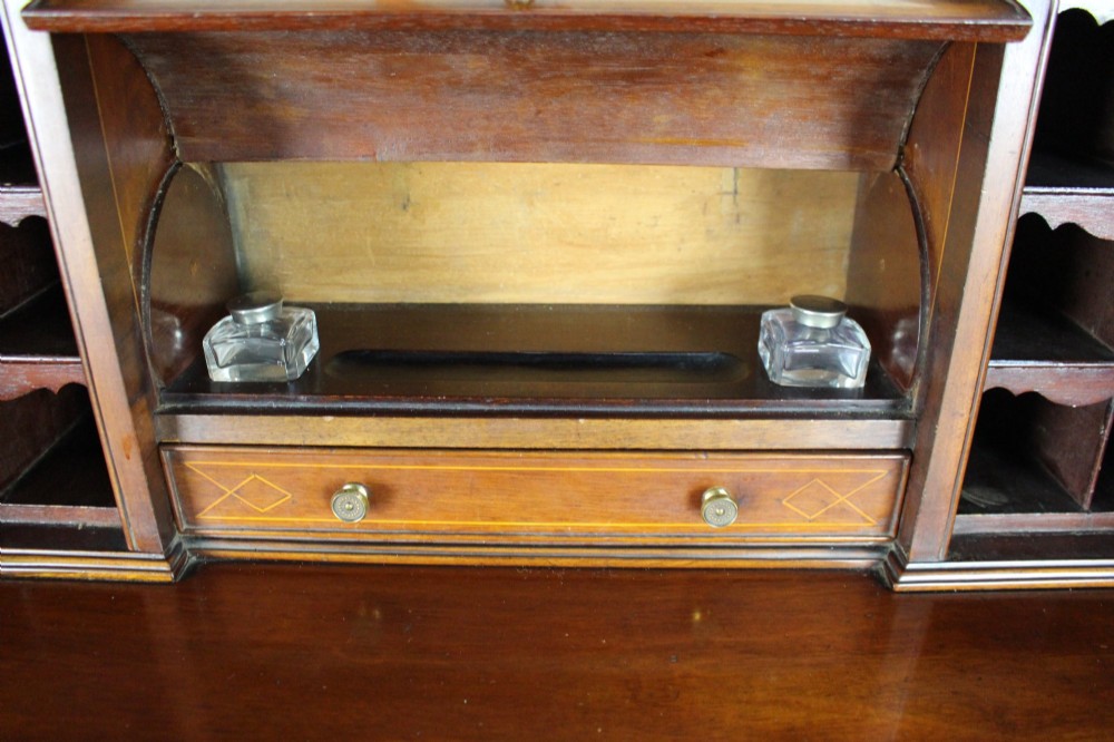 An Edwardian inlaid mahogany writing desk with a central drawer, satinwood urn marquetry, twin side cabinets, and tapered legs. View XI