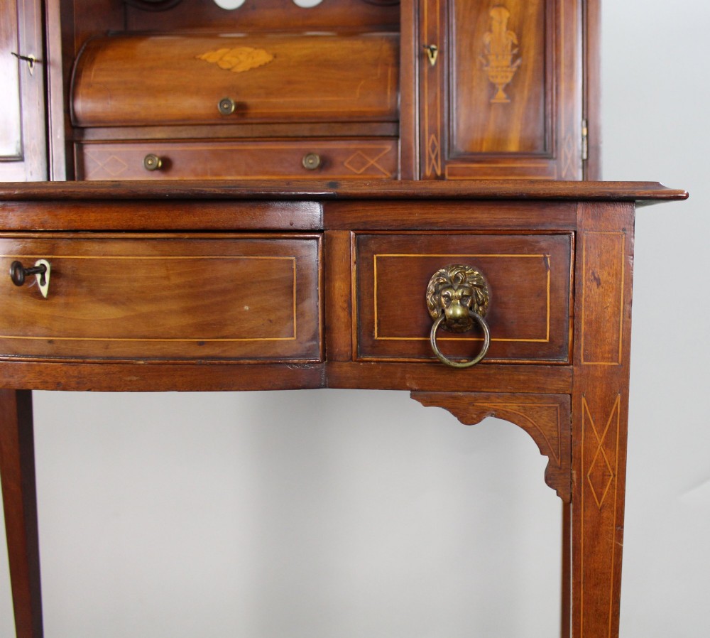 An Edwardian inlaid mahogany writing desk with a central drawer, satinwood urn marquetry, twin side cabinets, and tapered legs. View XV