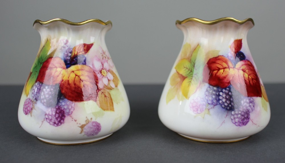 A pair of small white porcelain vases with wavy gilded rims, hand-painted with ripe blackberries, blossoms, and autumn foliage.