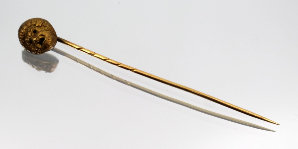 An antique Victorian gold stick pin featuring a relief-carved classical mask head atop a slender twisted shaft. View II