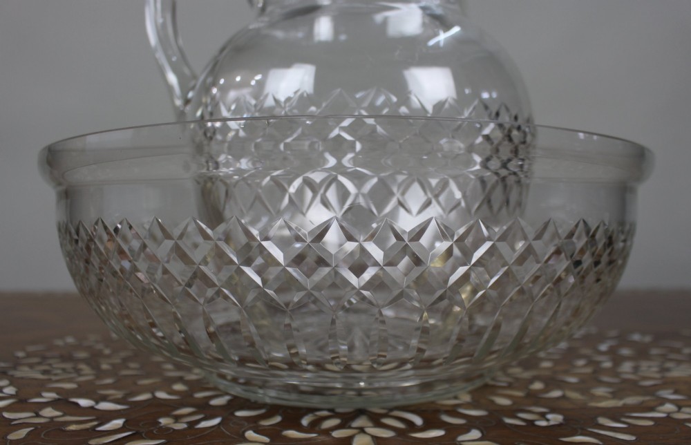 A clear cut crystal jug featuring a diamond motif seated inside a matching large round cut crystal basin. View III