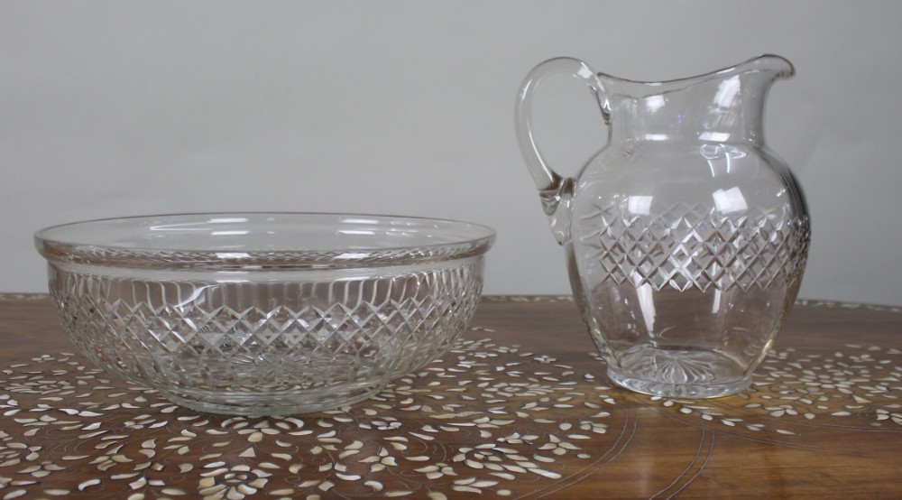 A clear cut crystal jug featuring a diamond motif seated inside a matching large round cut crystal basin. View IV
