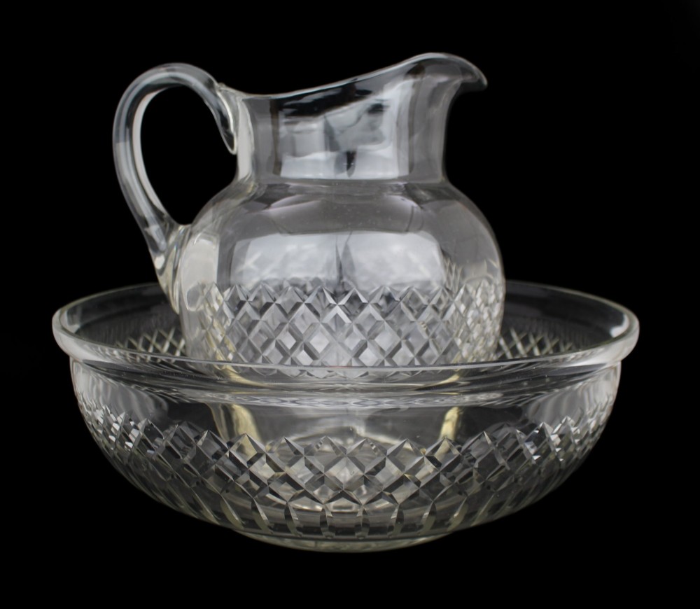 A clear cut crystal jug featuring a diamond motif seated inside a matching large round cut crystal basin. View V
