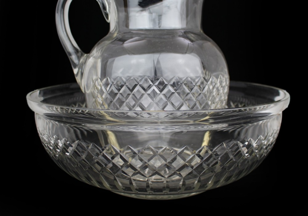 A clear cut crystal jug featuring a diamond motif seated inside a matching large round cut crystal basin. View VI