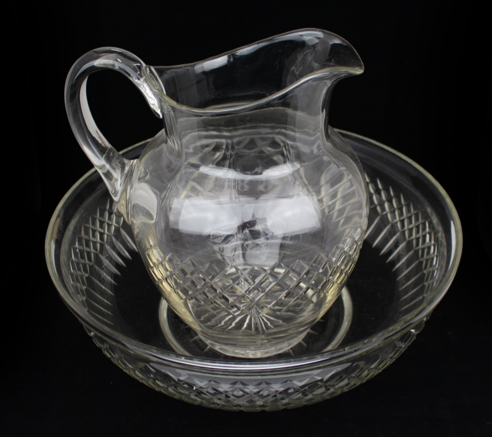A clear cut crystal jug featuring a diamond motif seated inside a matching large round cut crystal basin. View VII