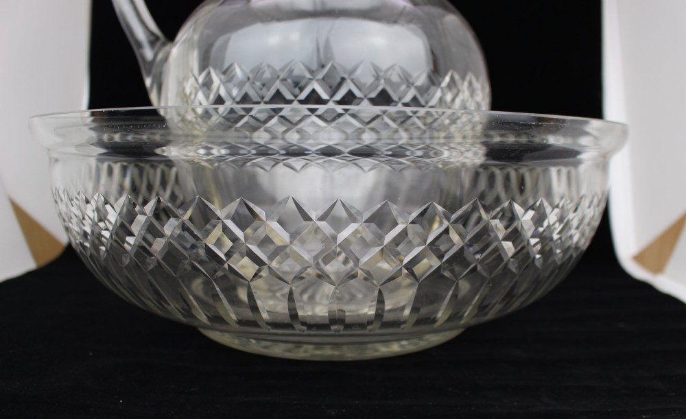 A clear cut crystal jug featuring a diamond motif seated inside a matching large round cut crystal basin. View VIII