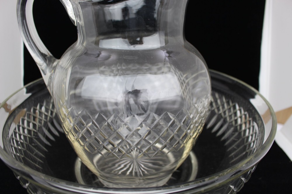 A clear cut crystal jug featuring a diamond motif seated inside a matching large round cut crystal basin. View IX