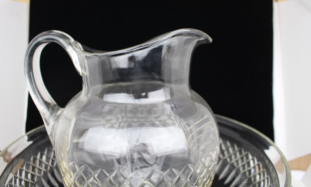 A clear cut crystal jug featuring a diamond motif seated inside a matching large round cut crystal basin. View X
