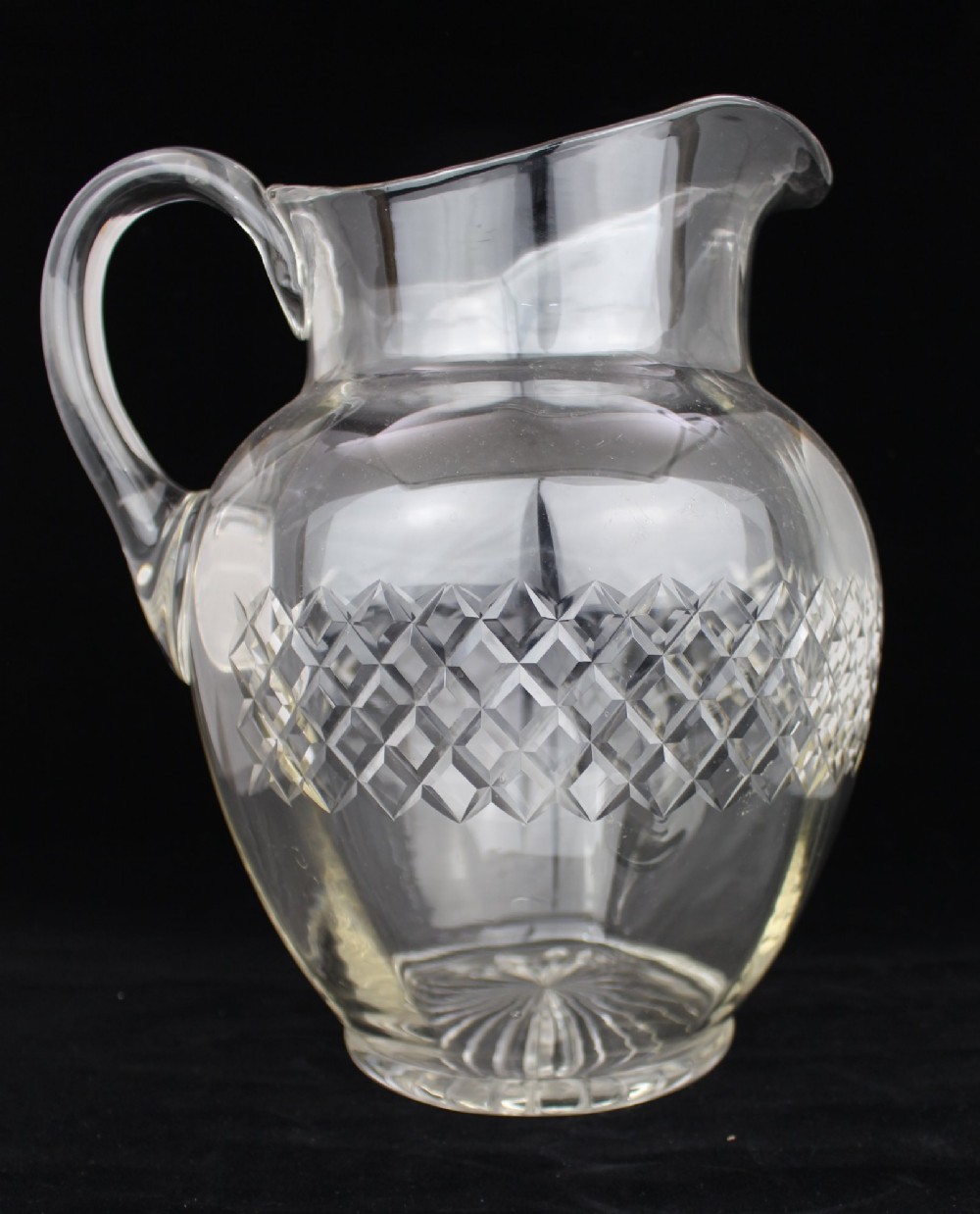 A clear cut crystal jug featuring a diamond motif seated inside a matching large round cut crystal basin. View XII