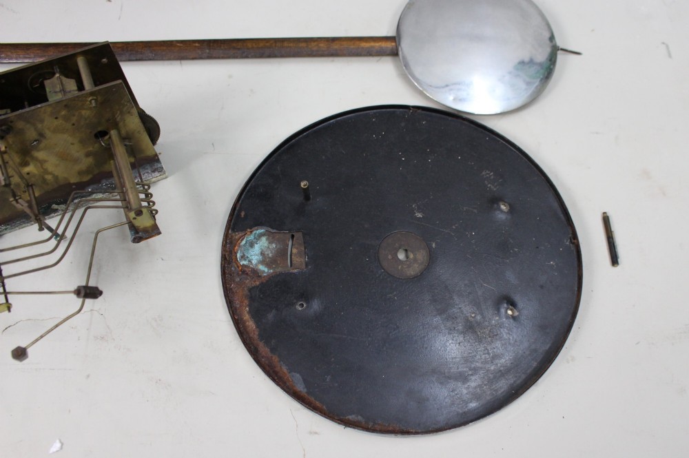 An Art Deco dark oak longcase clock case featuring a domed hood and glazed door alongside an unmounted brass movement, pendulum, chrome dial, and three cylindrical weights. View VI