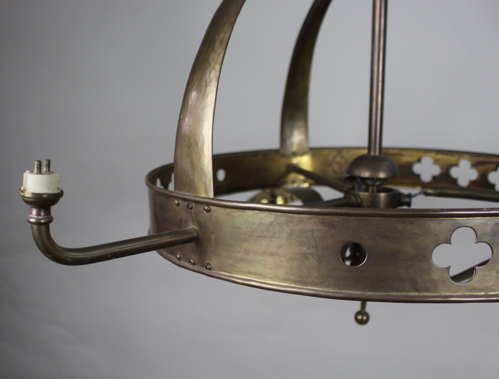 A Victorian Gothic Revival brass three-light gasolier frame featuring an arched cage and pierced trefoil band, presented alongside three ruffled opalescent glass shades. View III