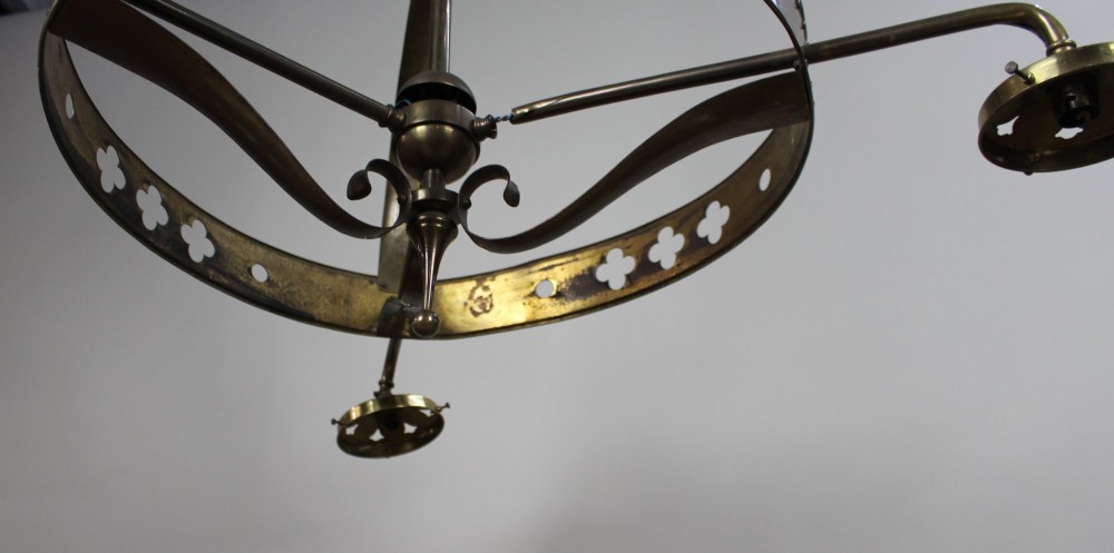 A Victorian Gothic Revival brass three-light gasolier frame featuring an arched cage and pierced trefoil band, presented alongside three ruffled opalescent glass shades. View IV