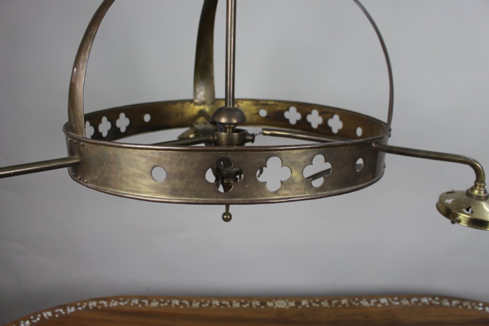 A Victorian Gothic Revival brass three-light gasolier frame featuring an arched cage and pierced trefoil band, presented alongside three ruffled opalescent glass shades. View V