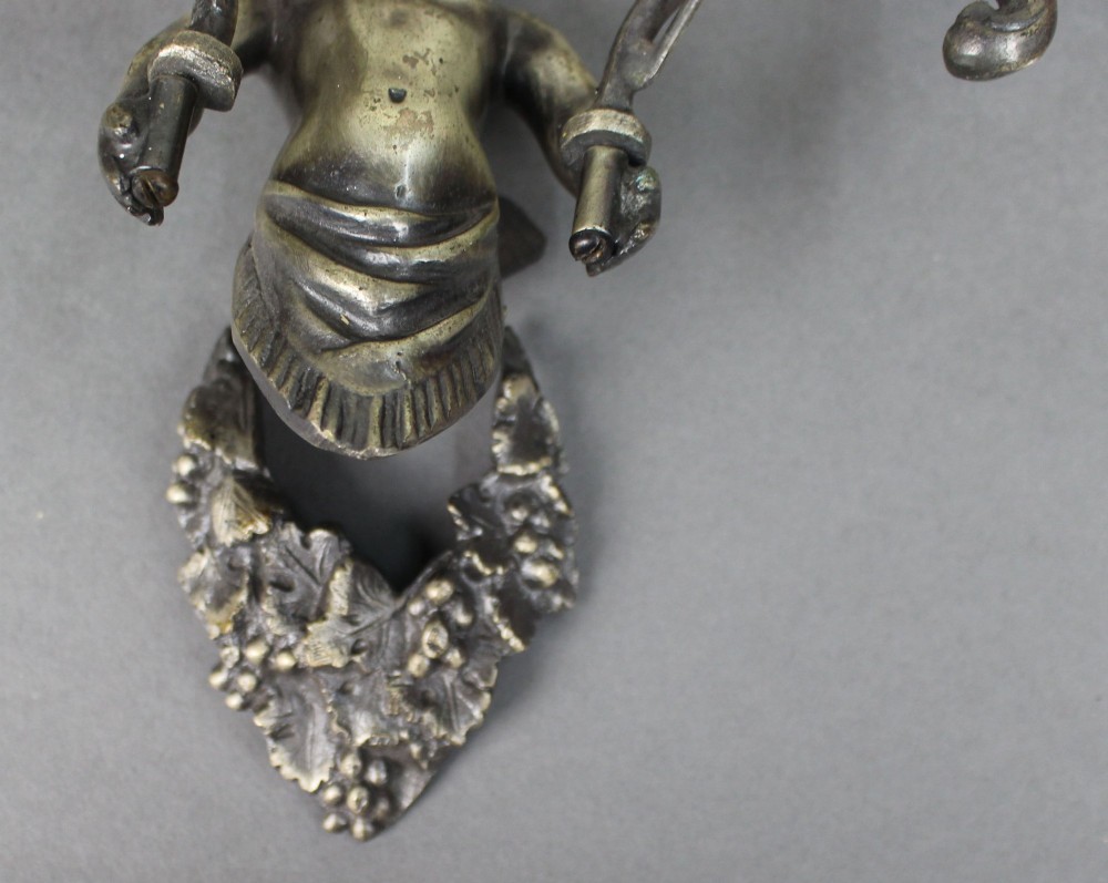 A pair of cast metal wall sconces featuring sculpted cherubs holding twin scroll arms decorated with ceramic floral motifs and electrical light sockets. View VI