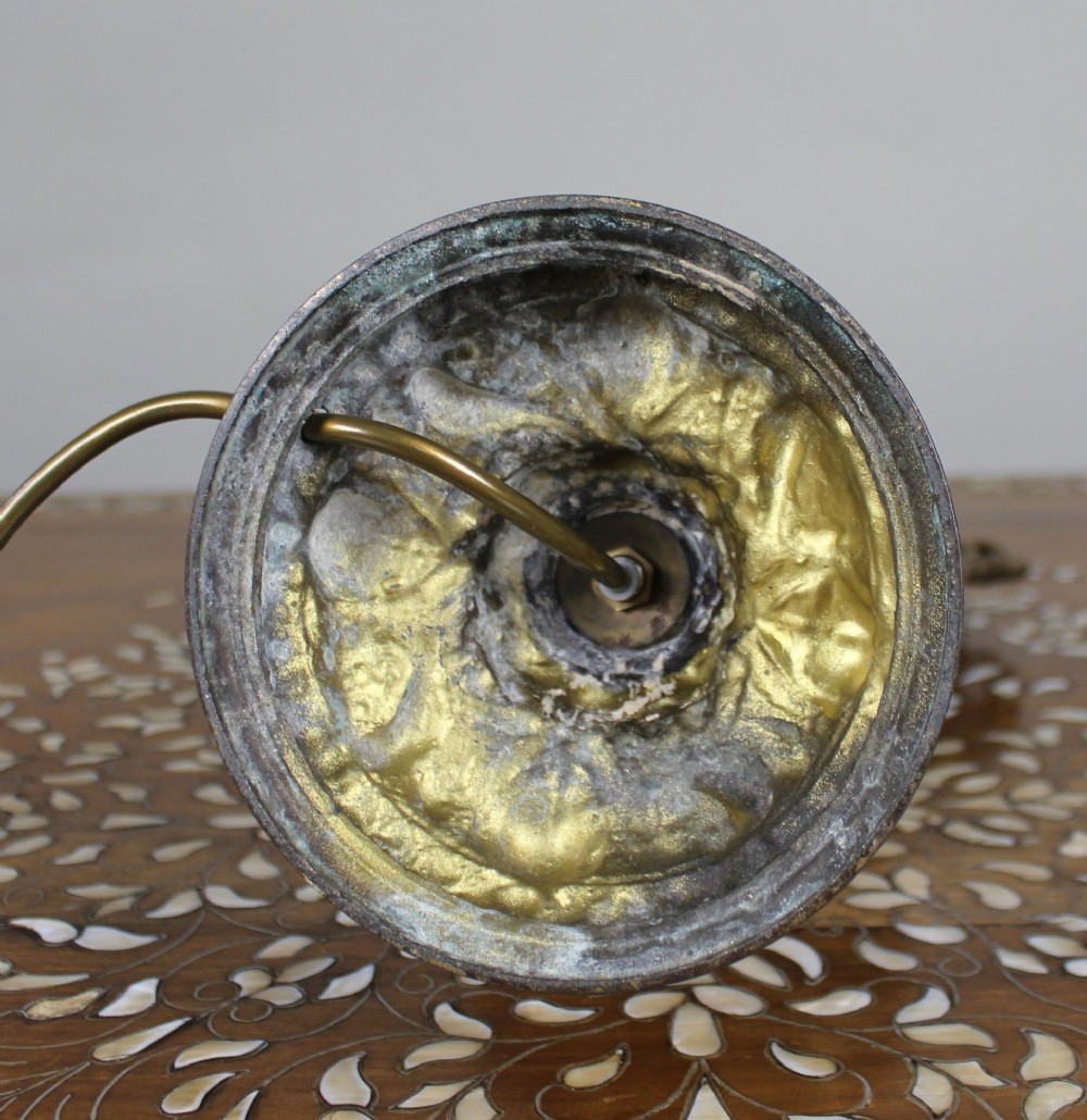 An ornate antique gilt metal table lamp fashioned in the shape of a Rococo ewer with a scrolled handle and intricate leaf relief patterns. View VI