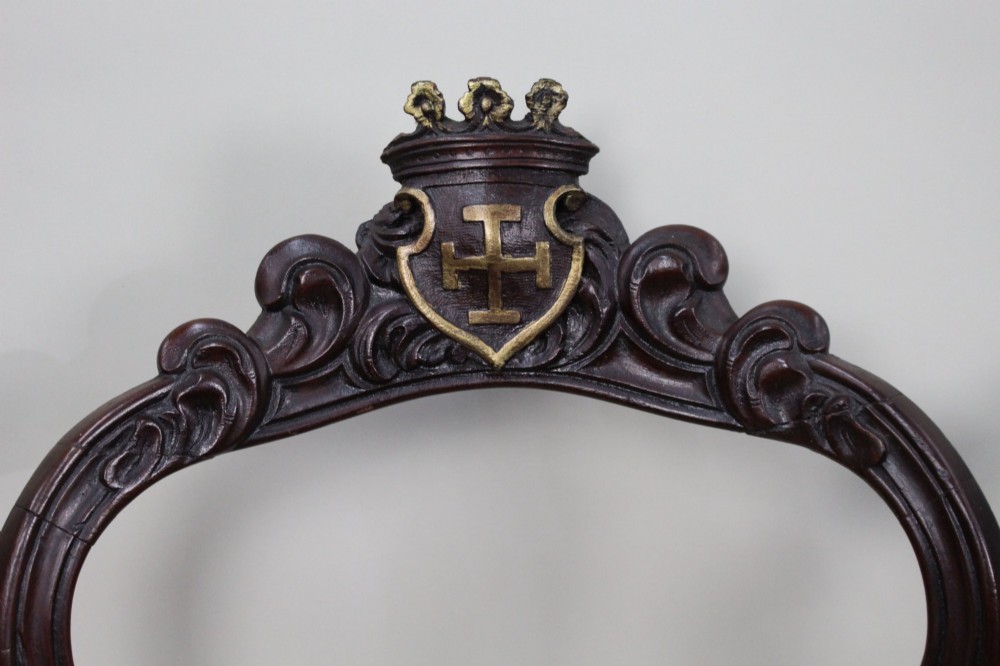 A set of four mid-Victorian dark mahogany side chairs featuring open-carved balloon backs topped with heraldic crest shields and cabriole front legs. View III