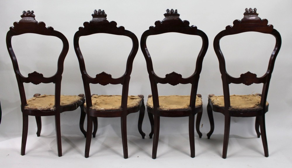 A set of four mid-Victorian dark mahogany side chairs featuring open-carved balloon backs topped with heraldic crest shields and cabriole front legs. View IX